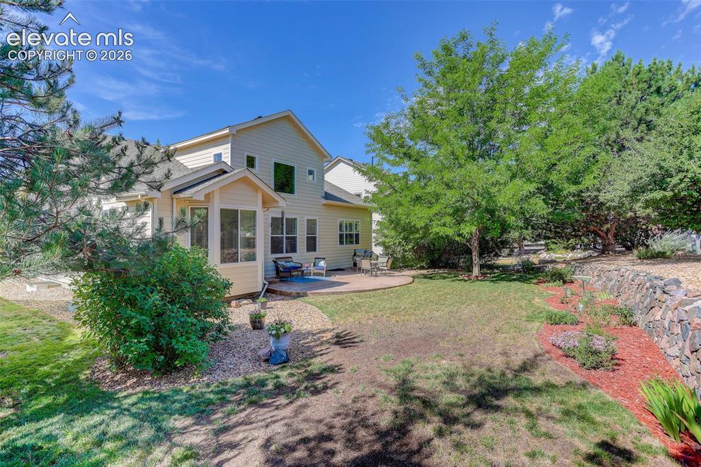Image 38 of 42: Spacious backyard with a curved paver patio, a screened-in porch, mature tr