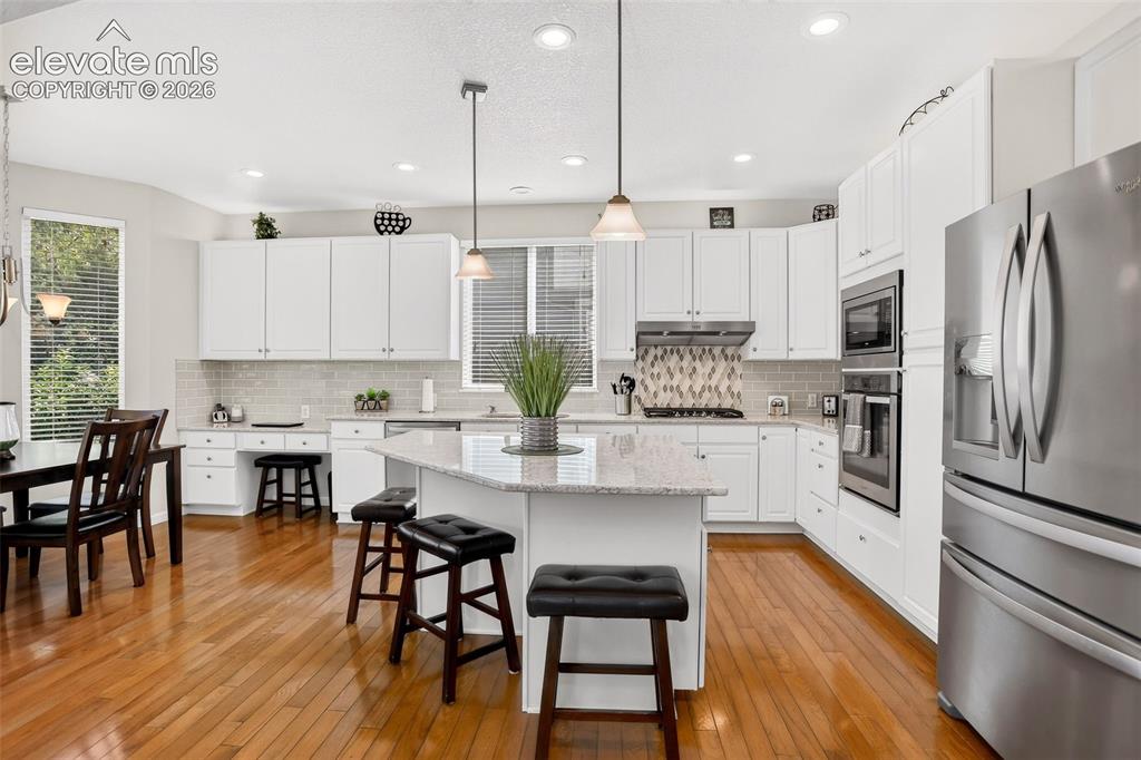 Image 9 of 42: Kitchen featuring wood-finish flooring, white cabinetry, a built-in oven, s