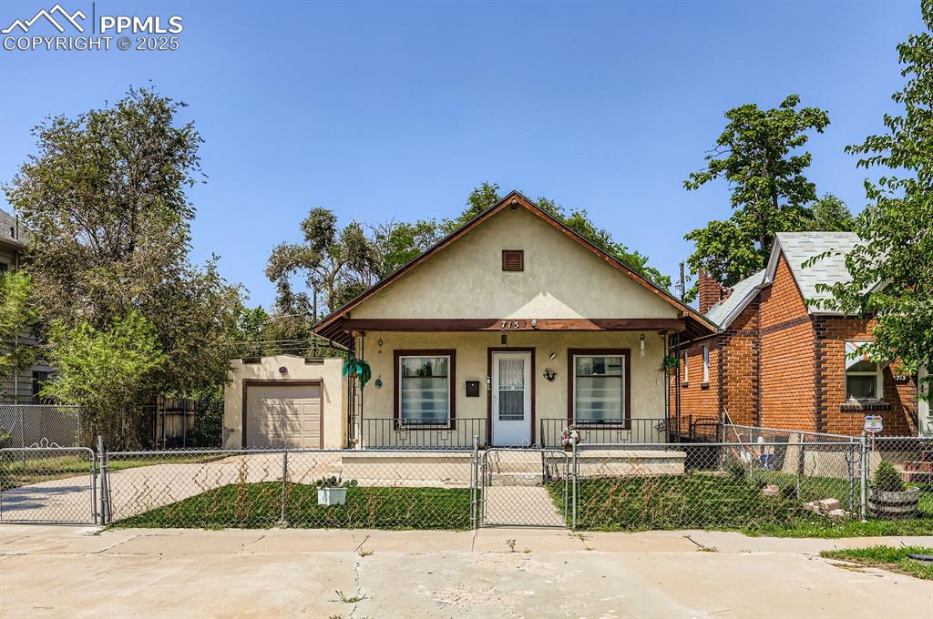 Image 1 of 10: View of front of property featuring covered porch, a gate, concrete drivewa