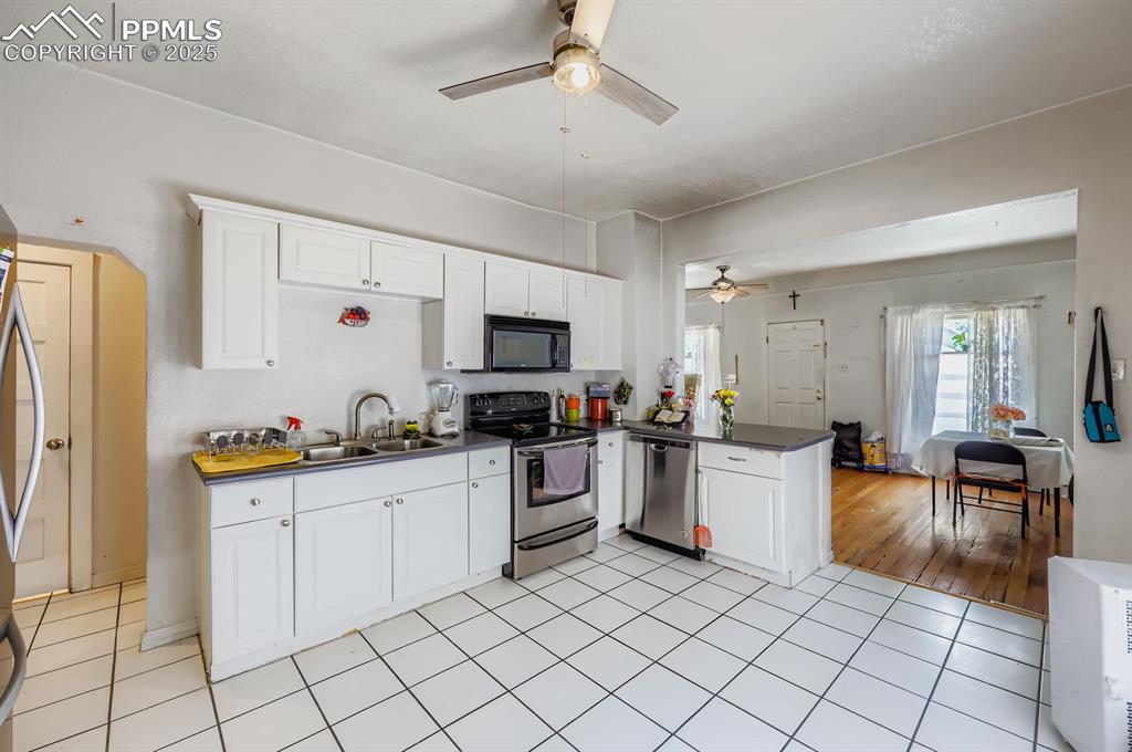 Image 3 of 10: Kitchen featuring stainless steel appliances, dark countertops, white cabin