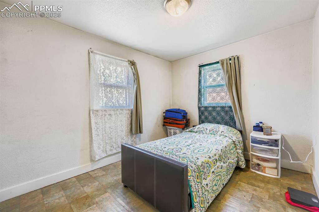 Image 5 of 10: Bedroom with multiple windows and stone finish floors
