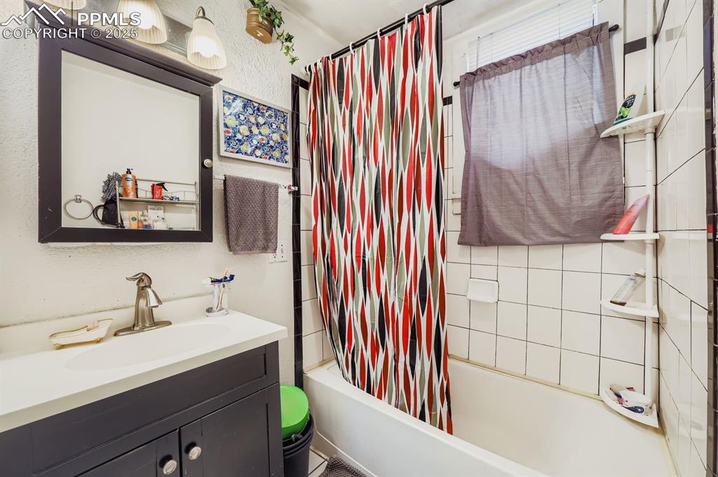 Image 6 of 10: Bathroom featuring shower / tub combo, vanity, and a textured wall