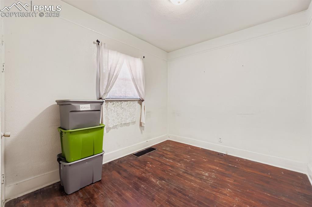 Image 7 of 10: Spare room featuring dark wood-style flooring and baseboards