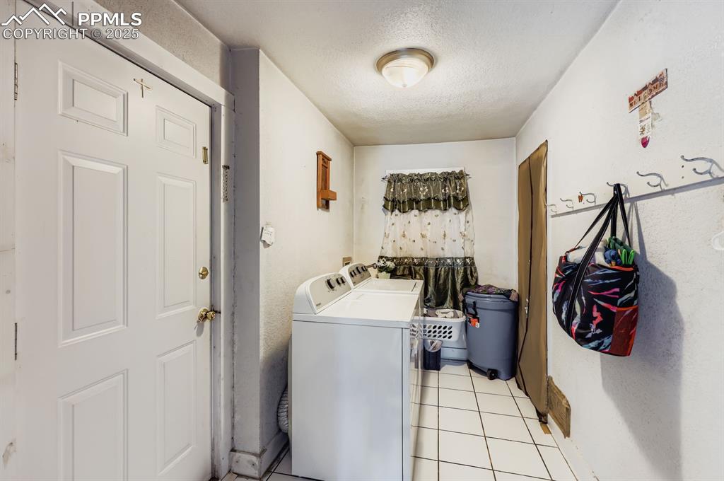 Image 9 of 10: Laundry area featuring a textured ceiling, light tile patterned flooring, a