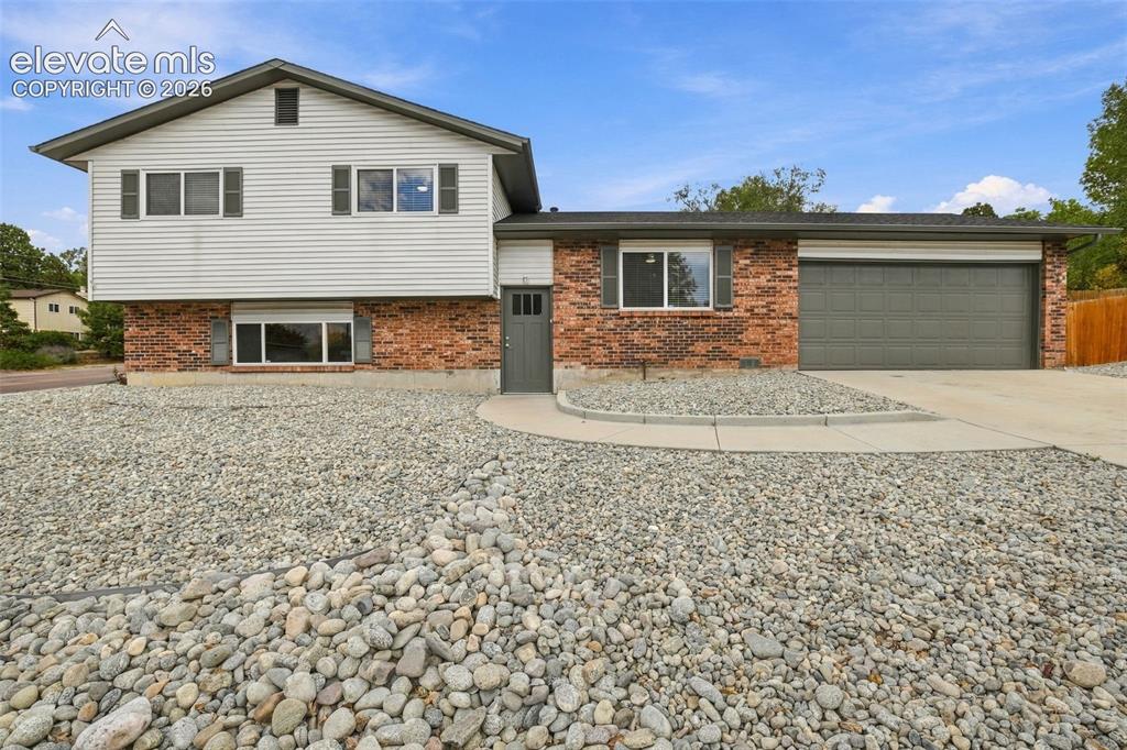 Image 1 of 50: Split-level exterior featuring light-toned horizontal siding, a red brick f