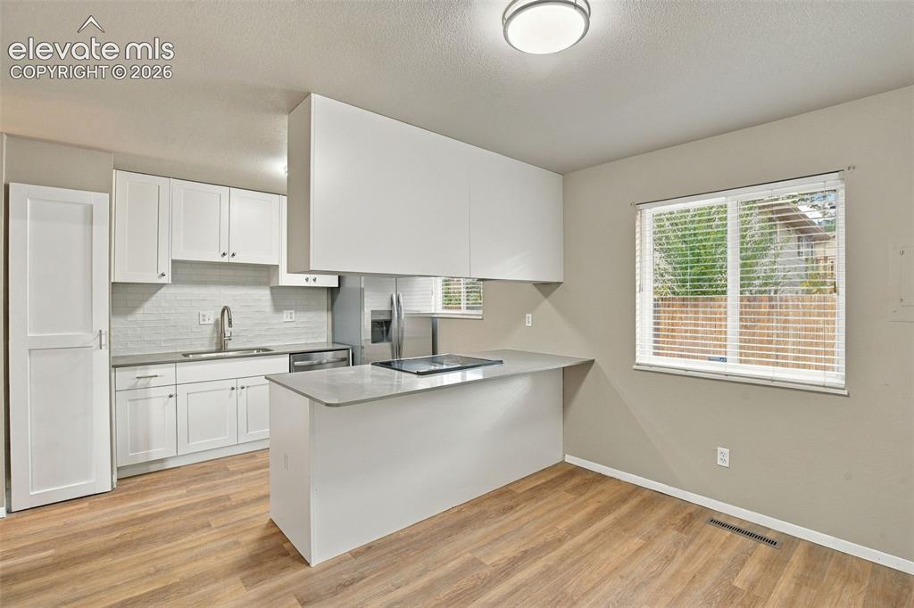 Image 10 of 50: Kitchen featuring white cabinetry, solid-surface countertops, a tile backsp