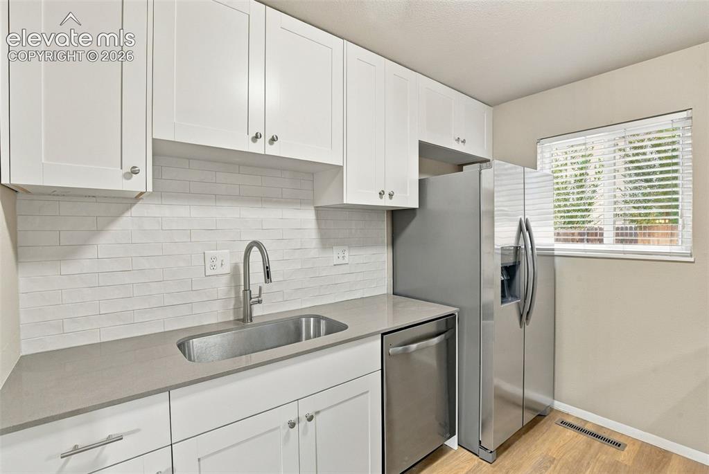 Image 13 of 50: Kitchen featuring white shaker-style cabinetry, a light-toned quartz counte