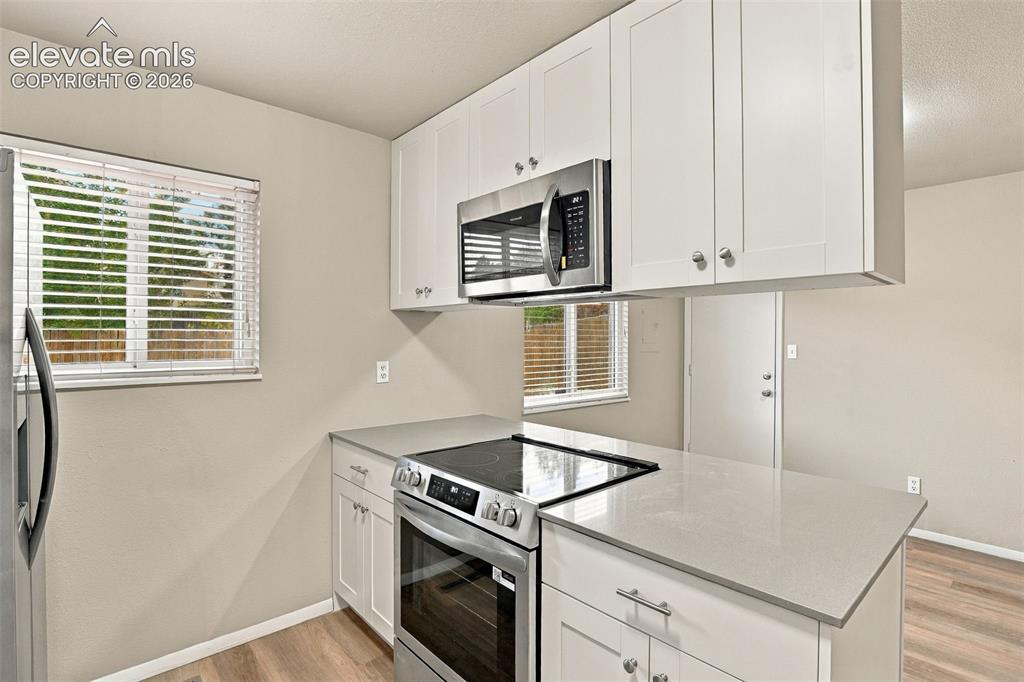 Image 14 of 50: Kitchen featuring white shaker-style cabinetry, stainless steel appliances,