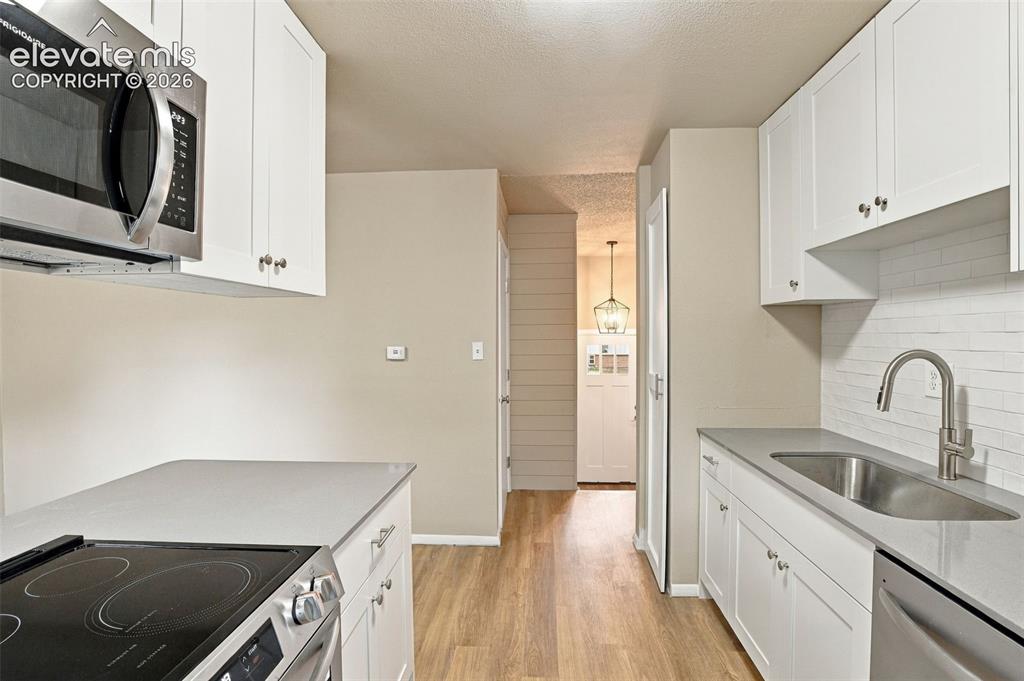 Image 16 of 50: Kitchen featuring white shaker-style cabinetry, solid-surface countertops, 