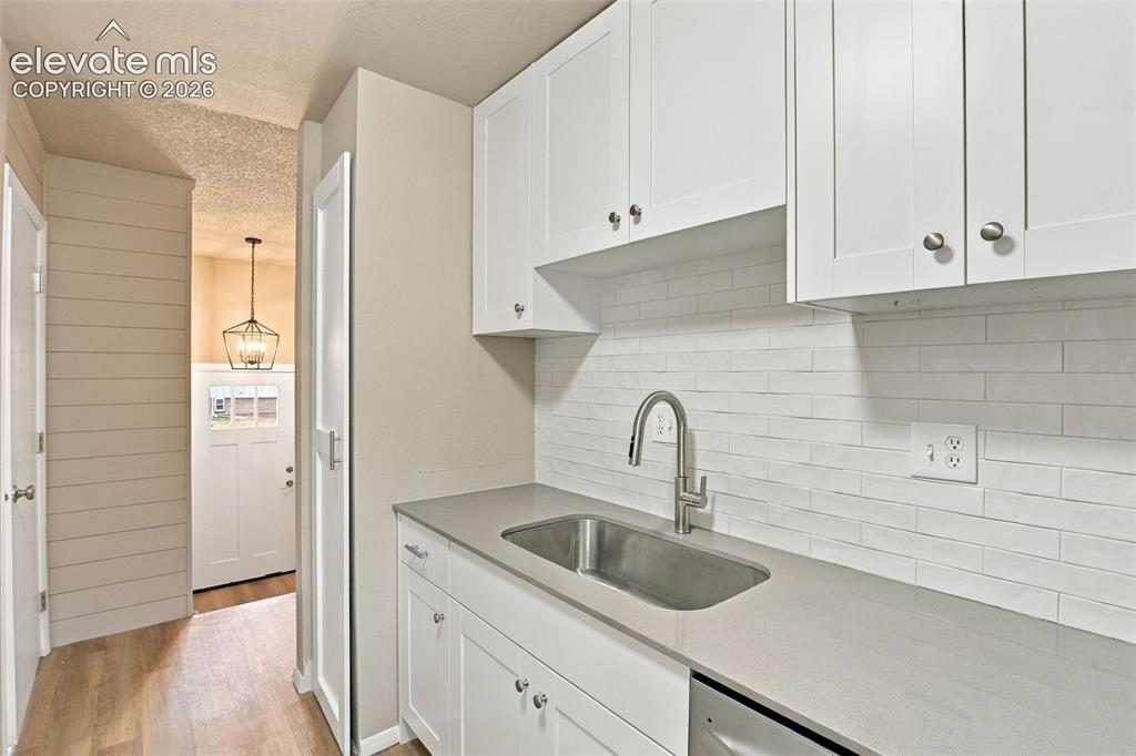 Image 17 of 50: White Shaker-style cabinetry, solid-surface countertops, horizontal plank w