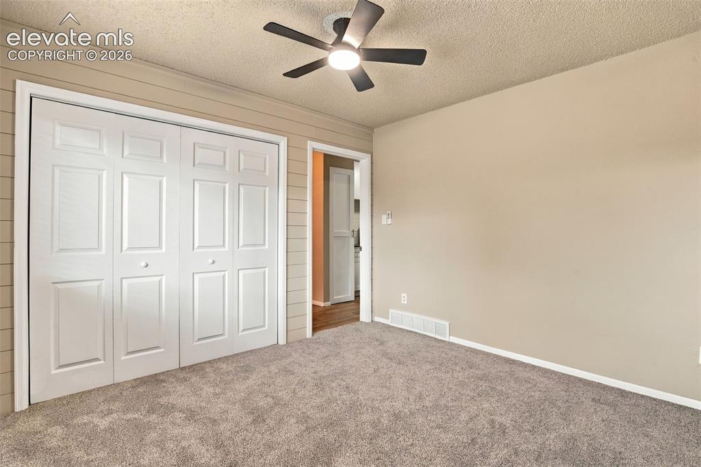 Image 19 of 50: Room featuring neutral carpeting, horizontal wall paneling, a ceiling fan w