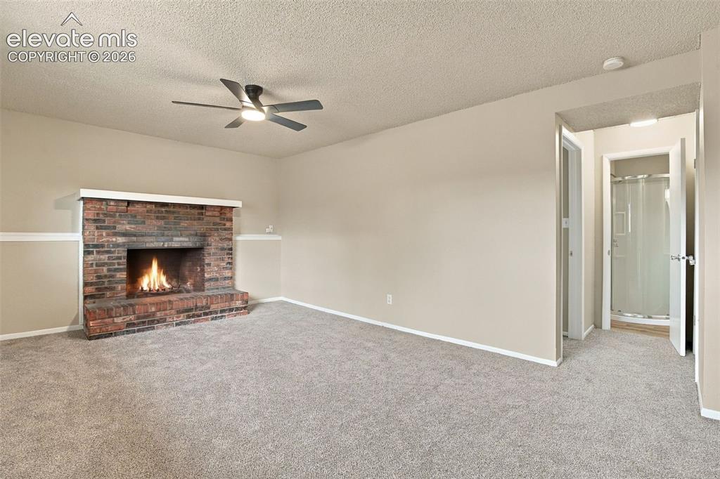 Image 21 of 50: Living area featuring a floor-to-ceiling brick fireplace, neutral carpeting