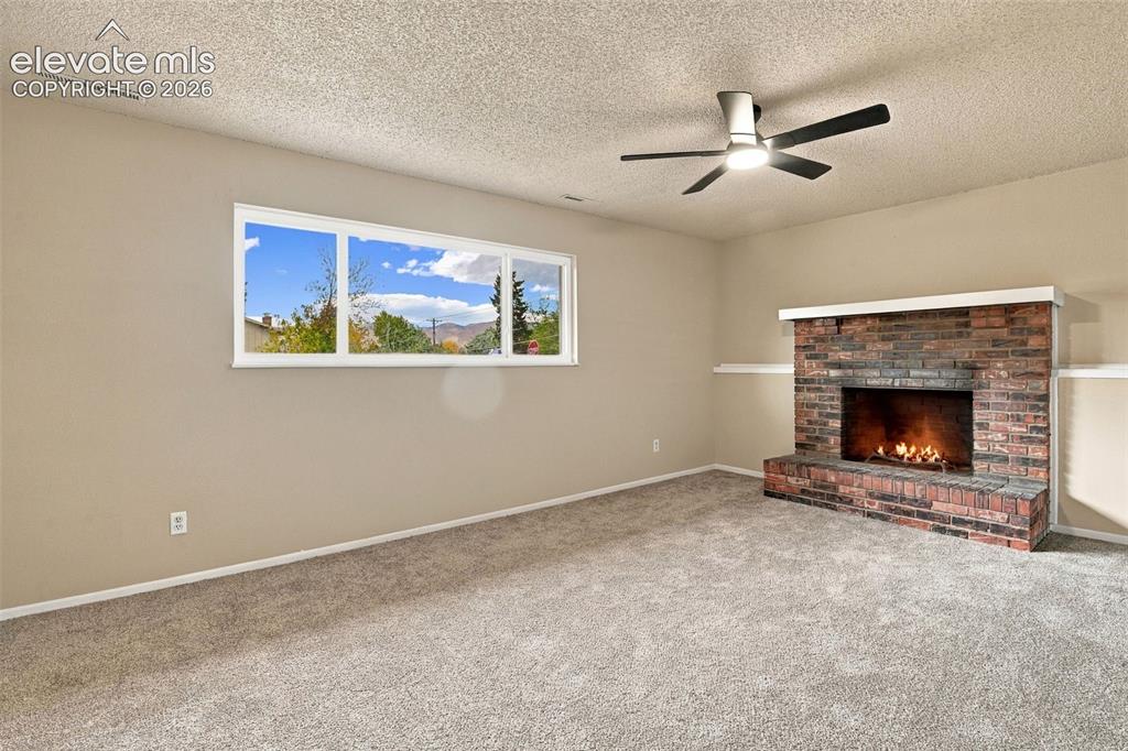 Image 22 of 50: Room featuring a brick fireplace with a mantle, neutral wall-to-wall carpet