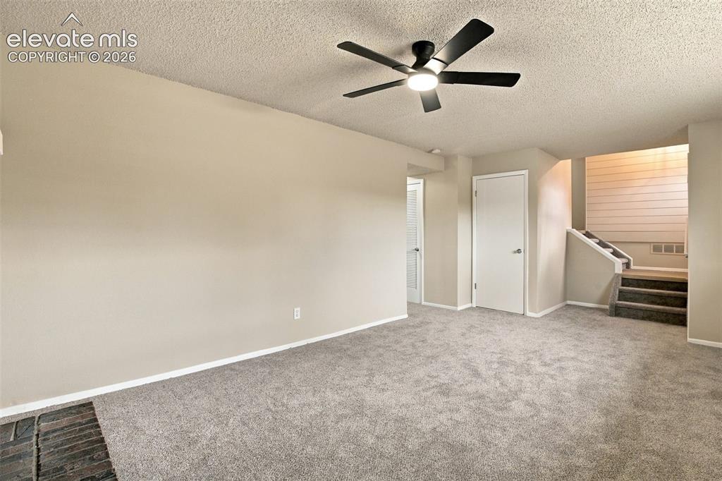Image 23 of 50: Living area featuring neutral wall tones, wall-to-wall carpeting, a dark-fi