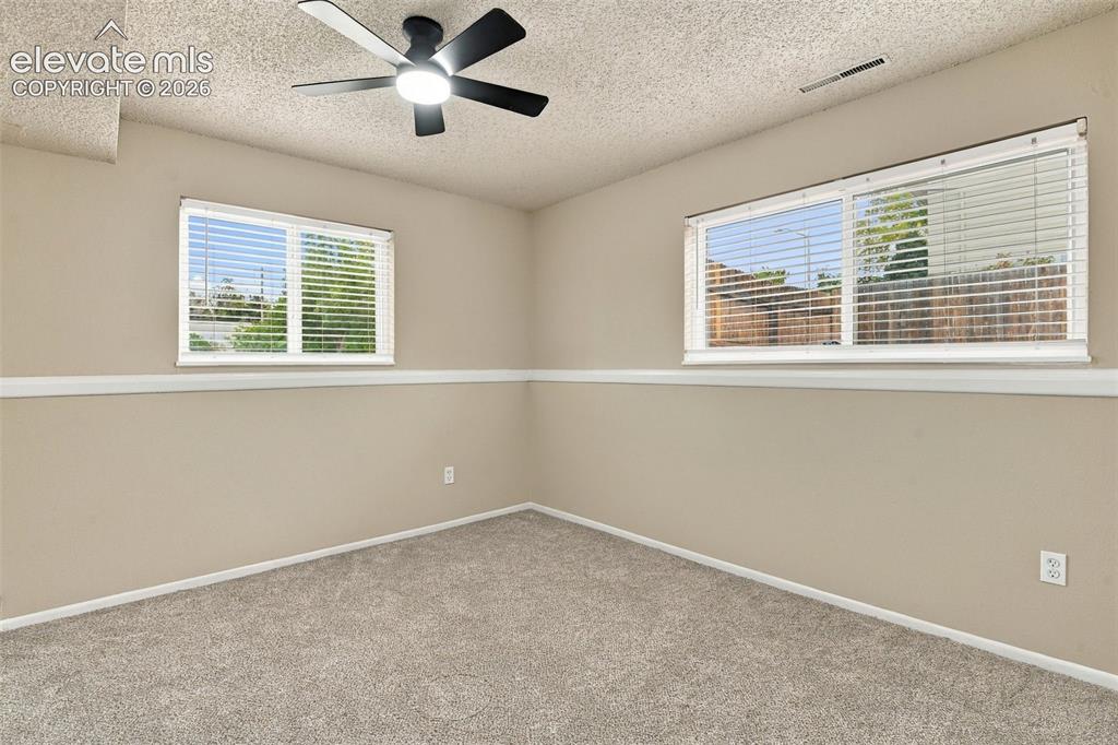 Image 25 of 50: Neutral-toned room featuring textured ceiling, carpeted flooring, white cha
