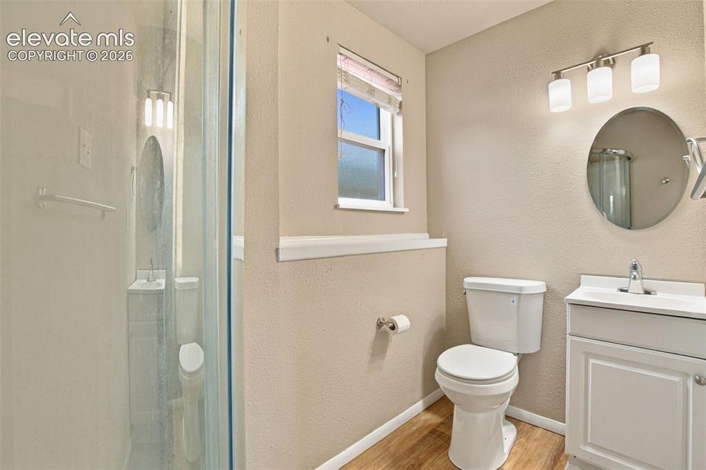 Image 27 of 50: Bathroom featuring a glass-enclosed shower, white vanity cabinet, circular