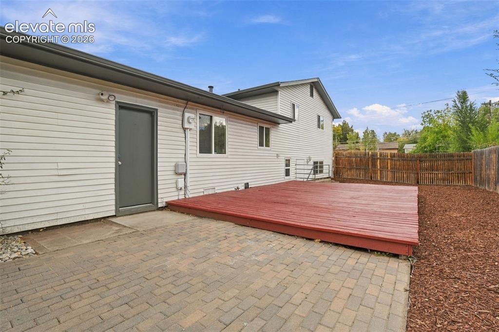 Image 29 of 50: Exterior area featuring a raised wood-finish deck, paver stone patio, horiz