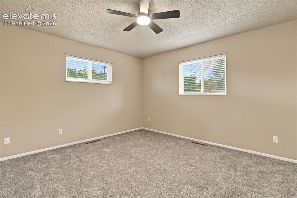 Image 3 of 50: Neutral-toned room featuring neutral-toned carpeting, two windows with hori