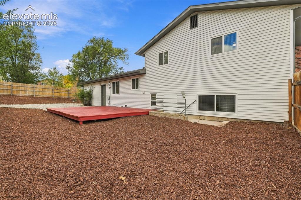 Image 30 of 50: Exterior rear elevation featuring horizontal siding, a red-painted wood dec