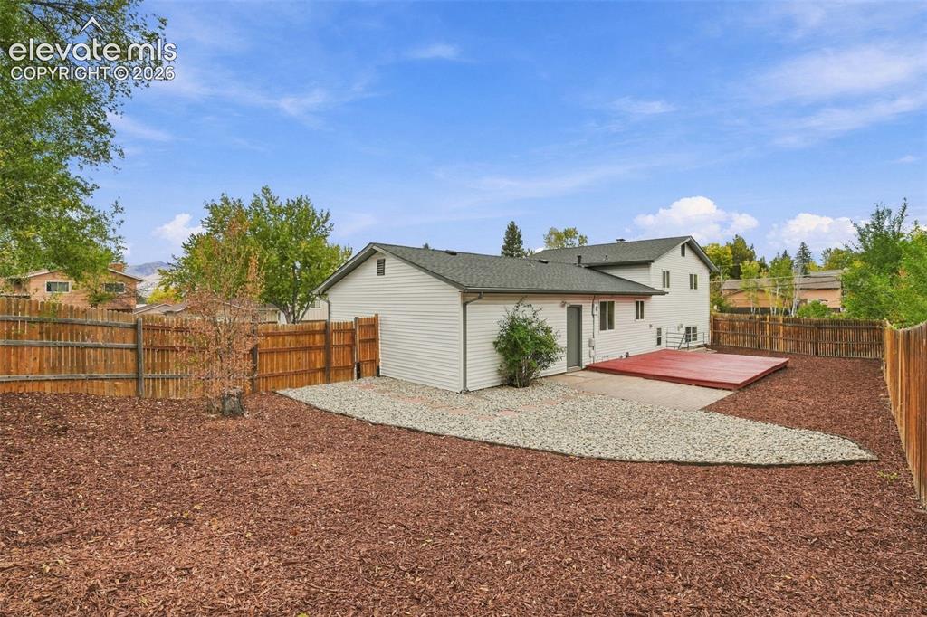 Image 32 of 50: Backyard featuring a raised wooden deck, partial gravel landscaping, perime