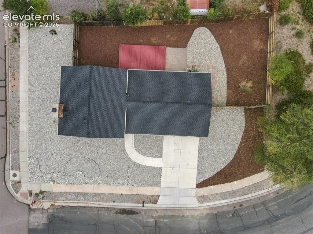 Image 33 of 50: Aerial view of the property featuring a dark-shingled roof, a paved concret
