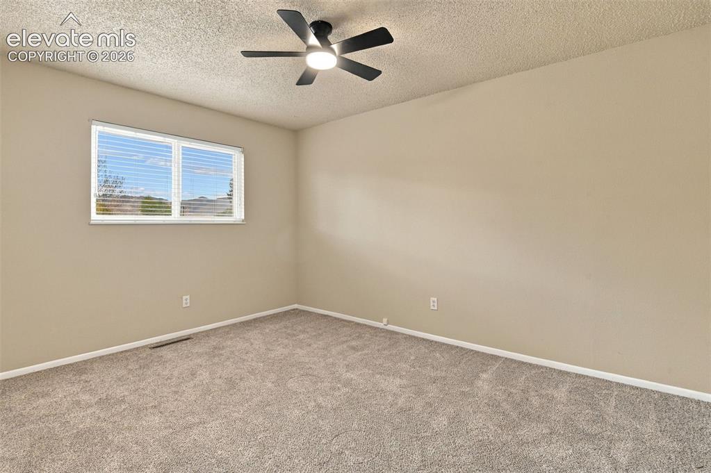 Image 5 of 50: Neutral-toned interior space featuring wall-to-wall carpeting, a multi-blad