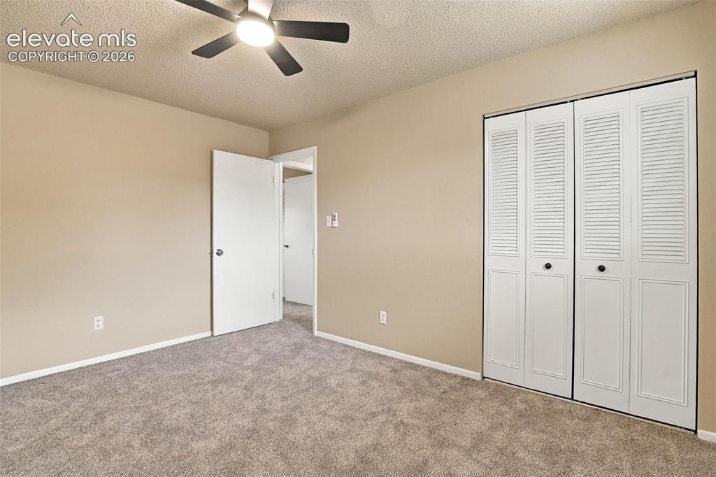 Image 6 of 50: Neutral wall-to-wall carpeting, ceiling fan with integrated lighting, and w