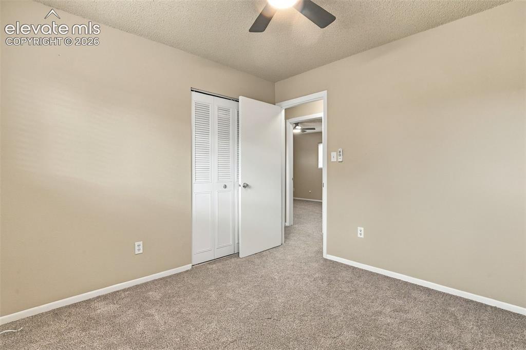 Image 8 of 50: Neutral-toned room featuring textured ceiling, carpeting, and louvered clos