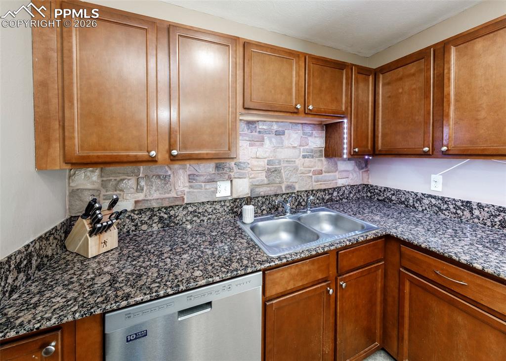 Image 16 of 39: Kitchen featuring stainless steel dishwasher, wood finish cabinetry, backsp