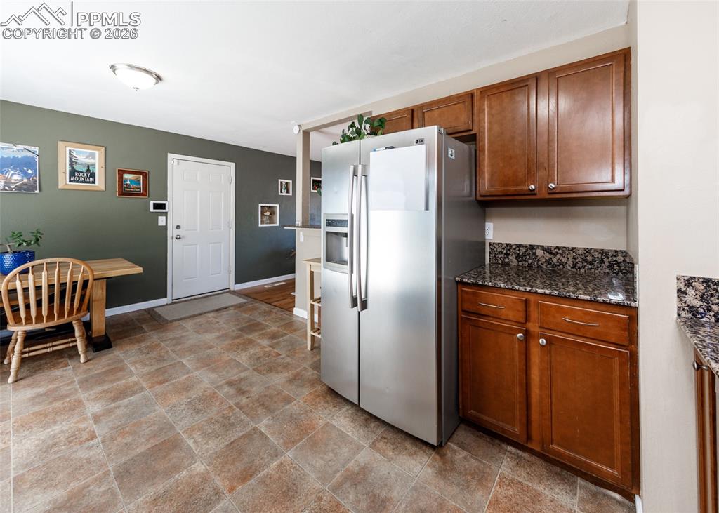 Image 18 of 39: Kitchen with stainless steel refrigerator with ice dispenser, dark stone co