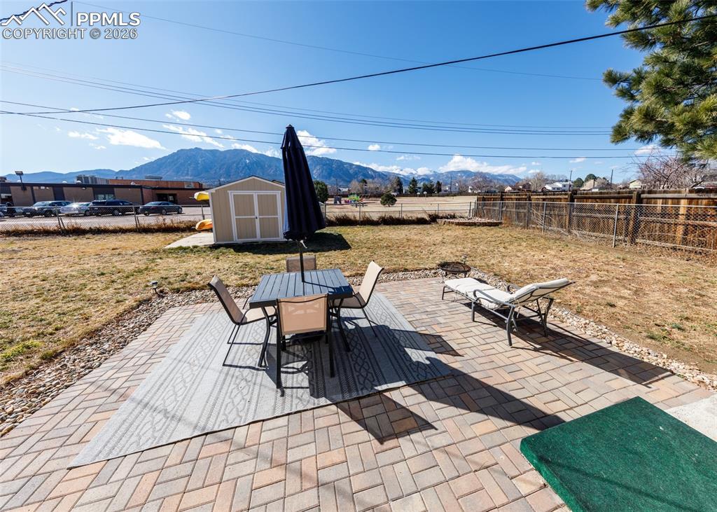 Image 24 of 39: Fenced backyard with a patio, a storage shed, outdoor dining space, and a m