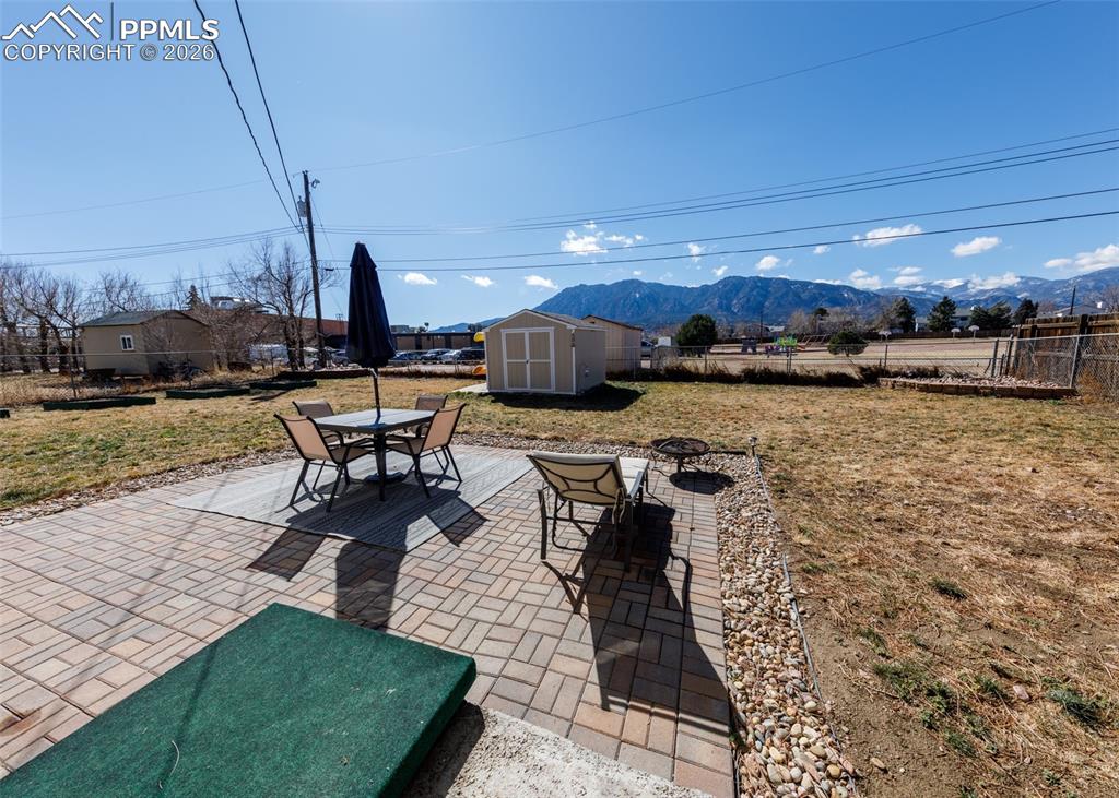 Image 25 of 39: Fenced backyard featuring outdoor dining space, a patio, a shed, and a moun