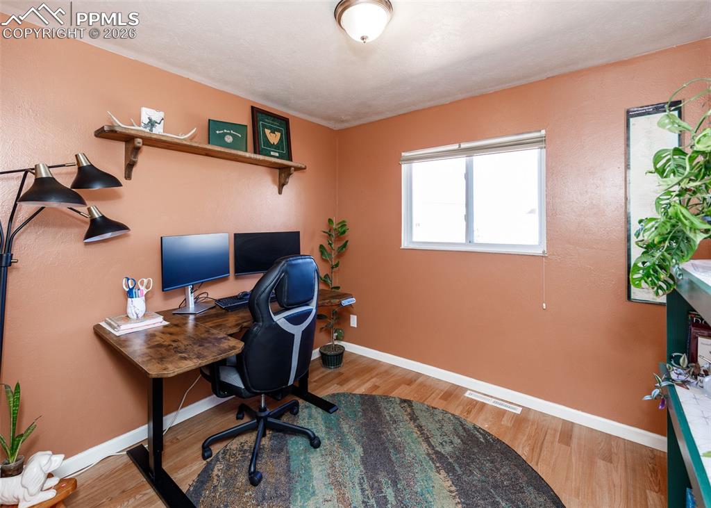 Image 32 of 39: Office area with light wood-style floors and baseboards
