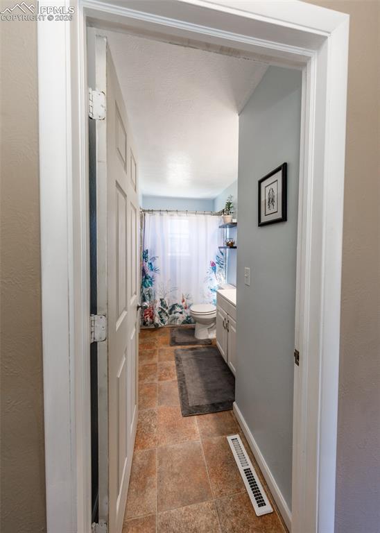 Image 35 of 39: Full bathroom featuring vanity, curtained shower, and stone tile flooring
