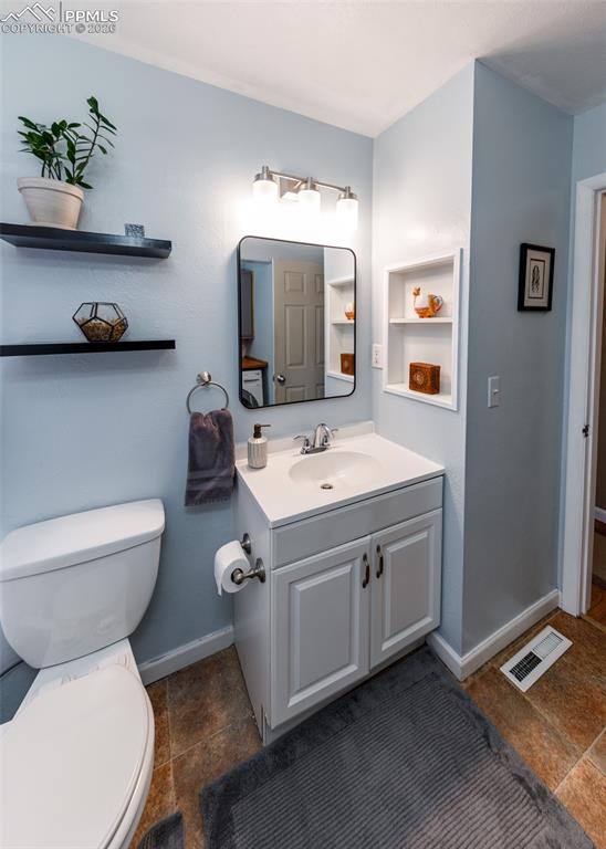 Image 36 of 39: Half bath with vanity and dark stone finish floors