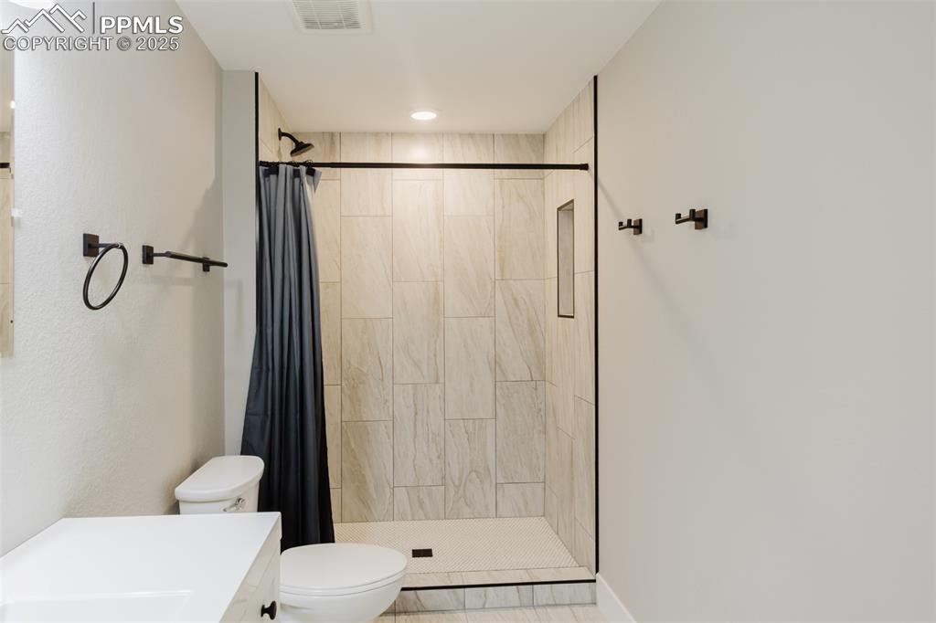 Image 24 of 31: This gorgeous tile shower has a tile inset. Black plumbing accents add the 