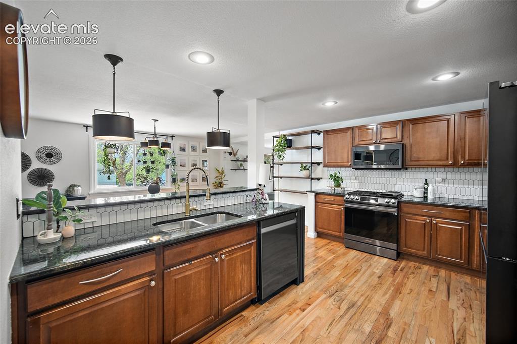 Image 10 of 43: Spacious kitchen featuring warm wood cabinetry, dark countertops, stainless