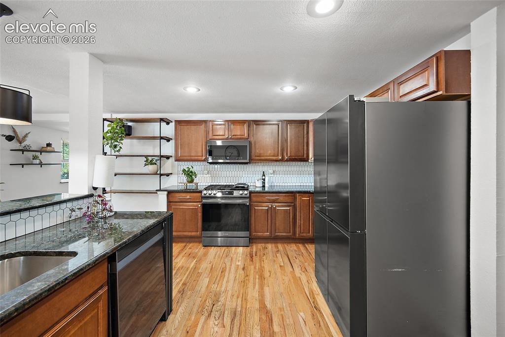 Image 11 of 43: Kitchen featuring wood-finish flooring, dark stone countertops, and a white