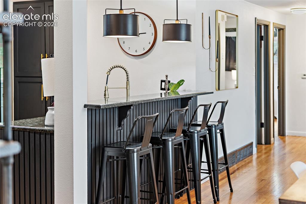 Image 14 of 43: Kitchen bar featuring a stone countertop with a gooseneck faucet, black bea