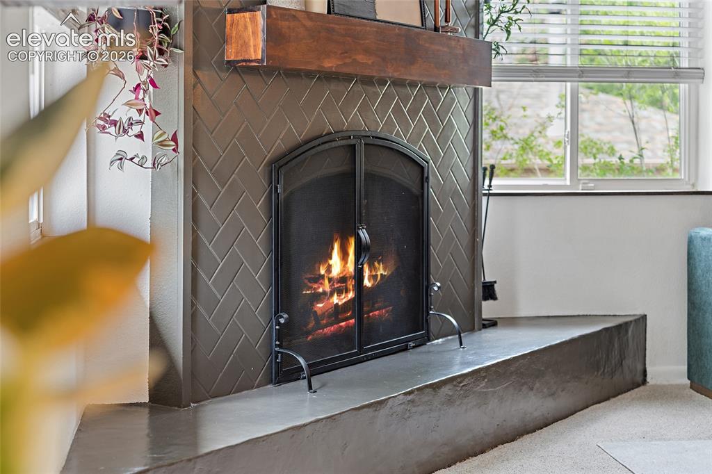 Image 21 of 43: Fireplace featuring herringbone tile surround, a dark wood mantel, and a co