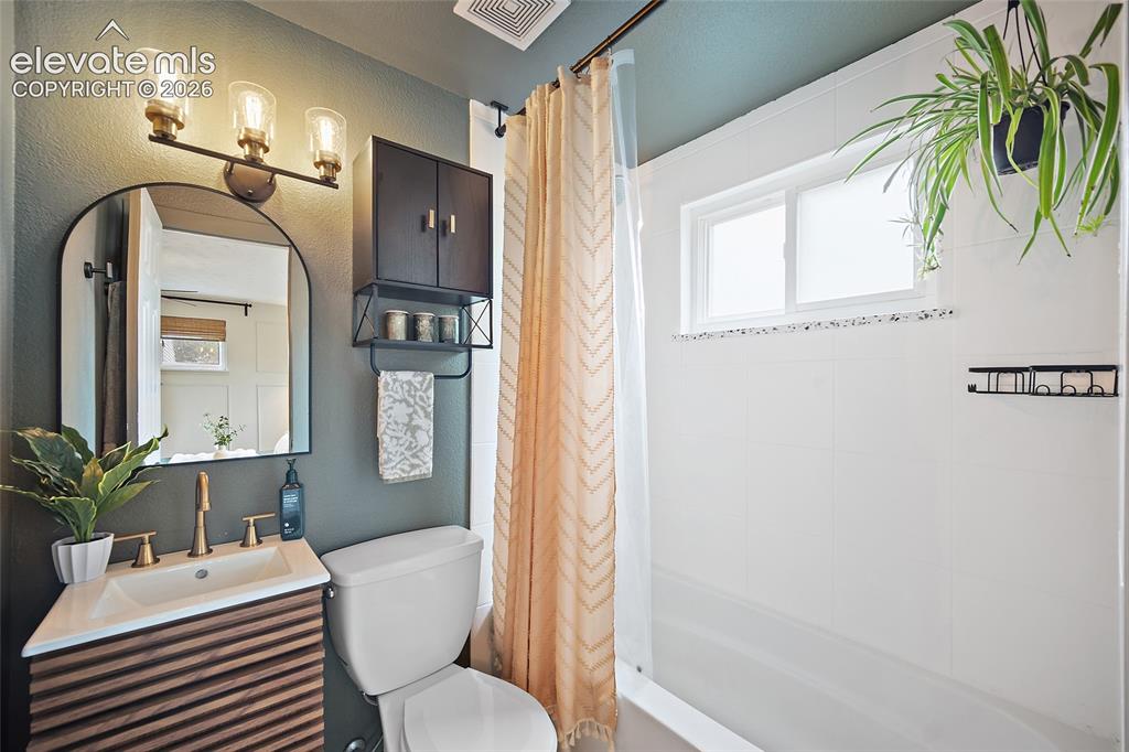 Image 26 of 43: Bathroom featuring a contemporary vanity with a wood-slat front and brushed