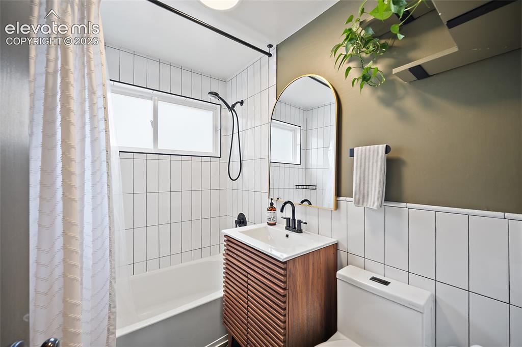 Image 29 of 43: Bathroom featuring a white subway tile shower surround with black fixtures,