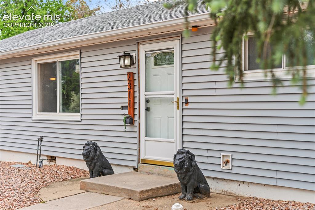 Image 3 of 43: Light gray horizontal siding exterior with a white front door featuring an 