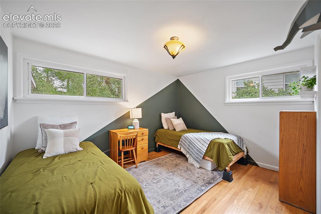 Image 32 of 43: Hardwood flooring and dual horizontal windows frame this room, which featur