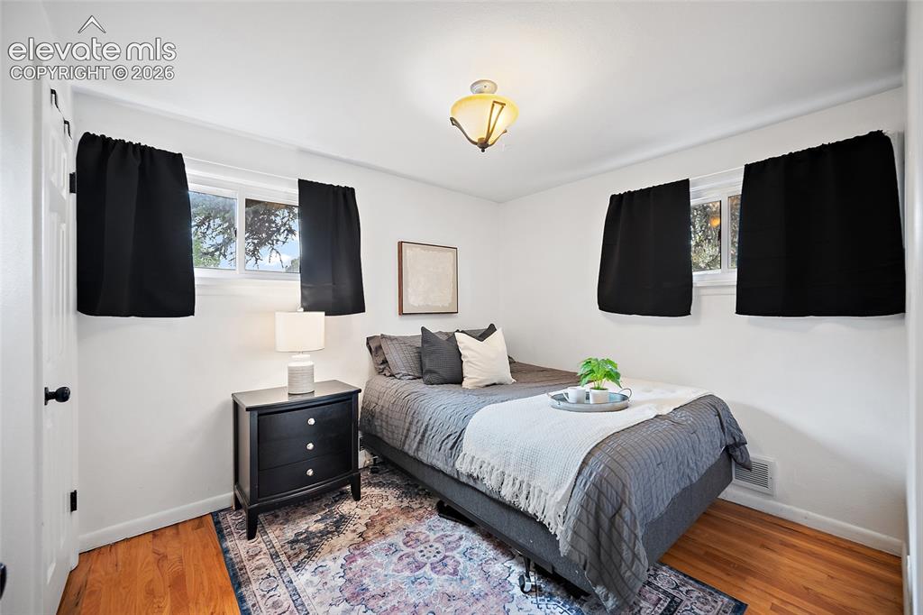 Image 35 of 43: Bright room featuring two windows with black privacy coverings, wood-finish