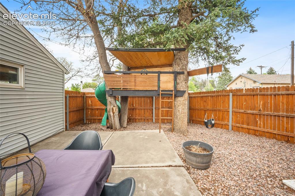 Image 37 of 43: Private backyard featuring a built-in treehouse with ladder access and a sl