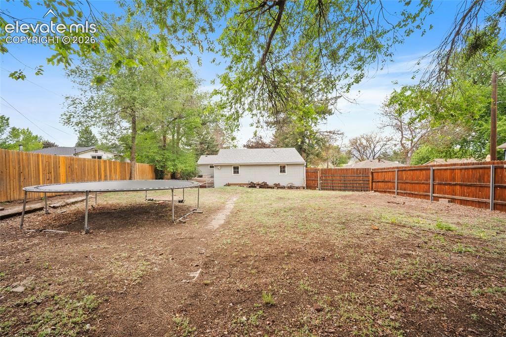 Image 40 of 43: Expansive backyard featuring a natural grass area, a wooden privacy fence, 