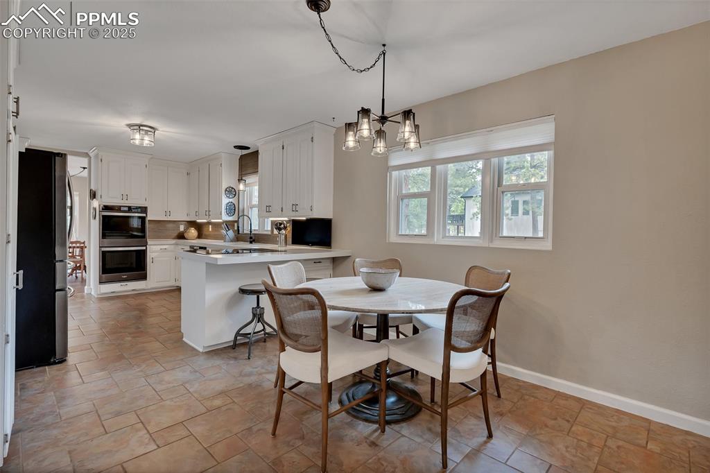 Image 13 of 41: Dining area with healthy amount of natural light, a chandelier, and light s