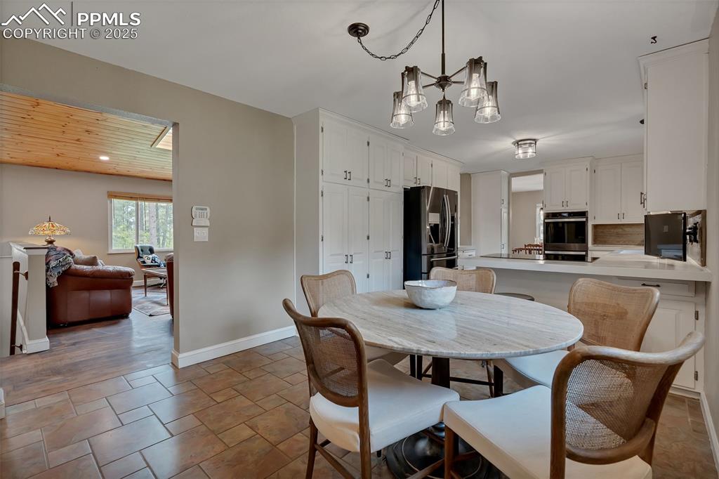 Image 14 of 41: Dining room with a chandelier, wooden ceiling, and light stone finish floor