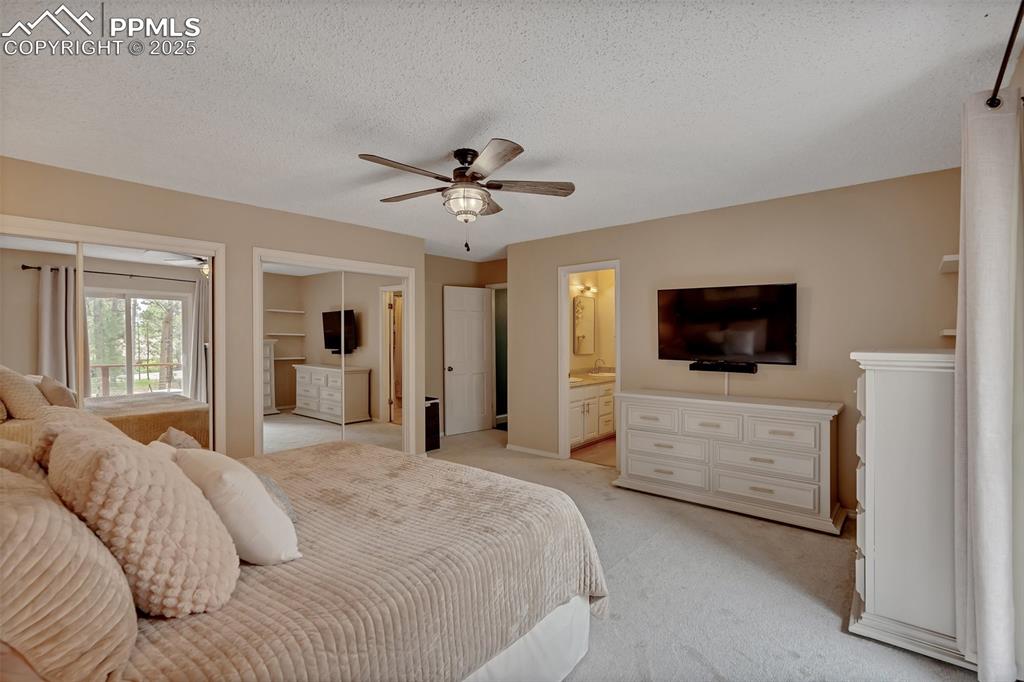 Image 17 of 41: Carpeted bedroom with a closet, a ceiling fan, a textured ceiling, and ensu